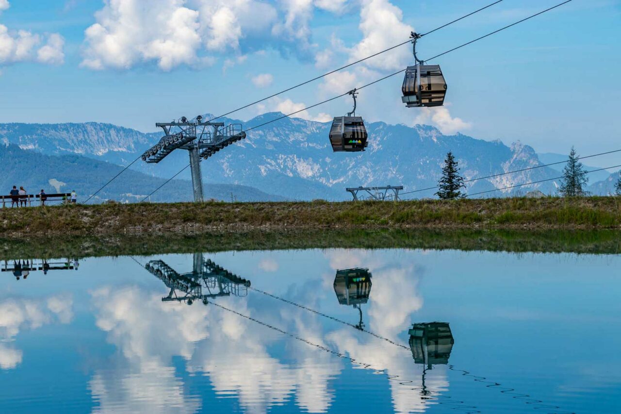 Zwei Gondeln der Jennerbahn über einem Speicherteich